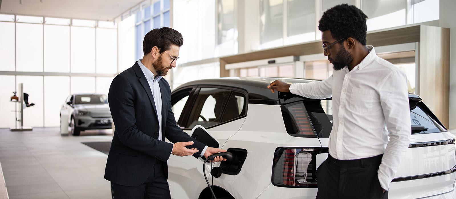 Commitment to Sustainability A car salesman showing off a plug-in electric vehicle to a customer.
